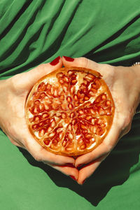 Hands of woman holding halved pomegranate