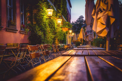 Empty chairs and tables against illuminated buildings in city