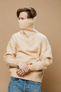 Rear view of woman standing against beige background