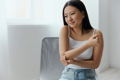 Portrait of young woman sitting on bed at home