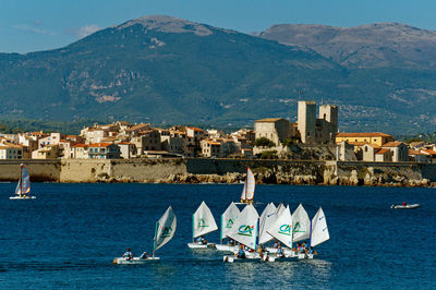 Sailboats in sea by buildings in city