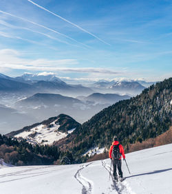 Rear view of man hiking on snow covered land