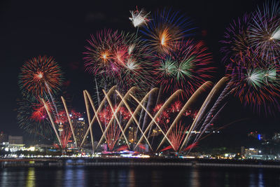 Firework display over river against sky at night