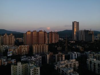 Buildings in city against clear sky during sunset