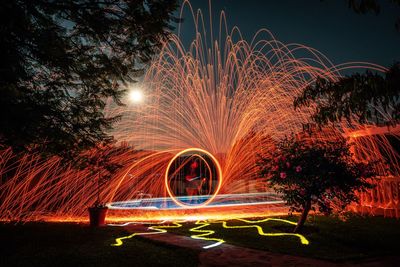 Light trails in park against sky at night