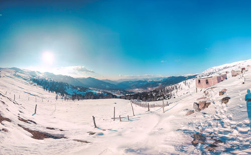 Scenic view of snow covered mountains against blue sky