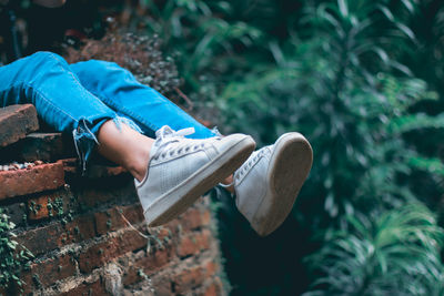 Low section of boy sitting on brick wall