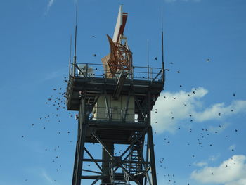 Low angle view of airport radar tower with birds