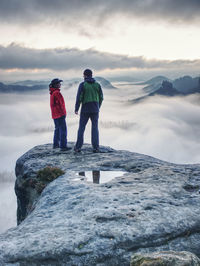 Happy couple with enjoy view after climbing top of rocky mountain. partners watch the beauty wild 