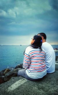 Rear view of couple sitting on beach