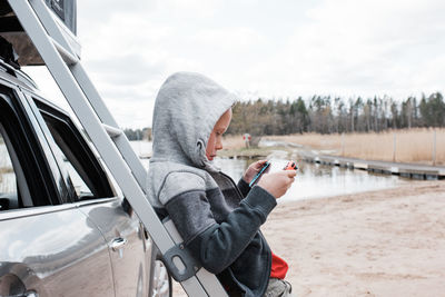 Boy playing nintendo games console whilst camping with his family