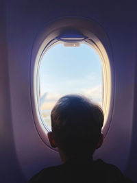 Rear view of woman looking through window