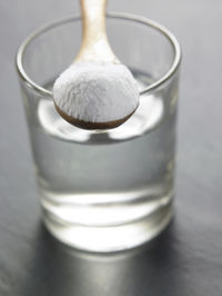 Close-up of powdered sugar with water in drinking glass on table
