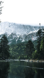 Scenic view of lake by snowcapped mountains against sky
