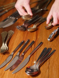 Cropped image of hand arranging kitchen utensils on table