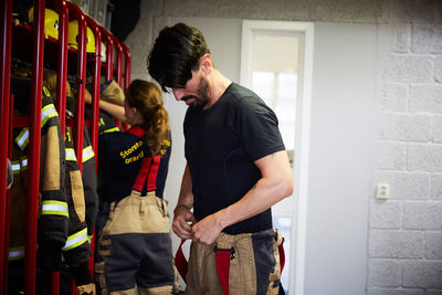 Male and female firefighters wearing protective workwear in locker room at fire station