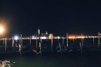 Boats moored in sea against sky at night