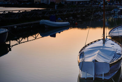 Boats moored in harbor at sunset