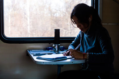 Woman sitting and writing in train 