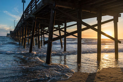 Pier over sea against sky during sunset