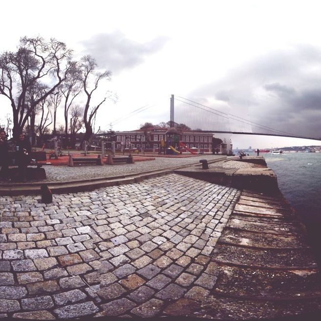 sky, built structure, architecture, building exterior, water, cloud - sky, cloudy, pier, overcast, river, sea, cloud, day, outdoors, cobblestone, railing, the way forward, no people, weather, roof