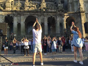 Instructors teaching dance to people against historic building