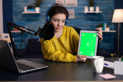 Young woman using mobile phone while sitting on table