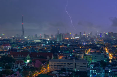 Illuminated cityscape against sky at night