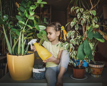 Full length of cute boy sitting in potted plant