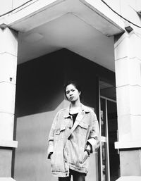 Portrait of young woman standing against building