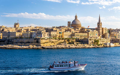 Boats in sea with buildings in background