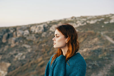 Portrait of young woman looking away against sky