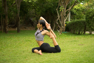 Woman practicing yoga on grassy field at public park