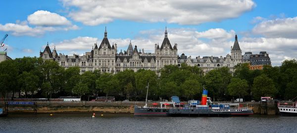 View of boats in river against cloudy sky