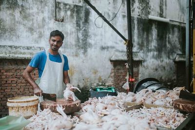 Portrait of butcher cutting meat at market stall