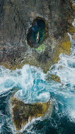 Drone view of man swimming in tidal pool