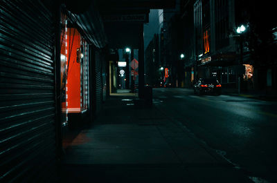 Illuminated street amidst buildings in city at night