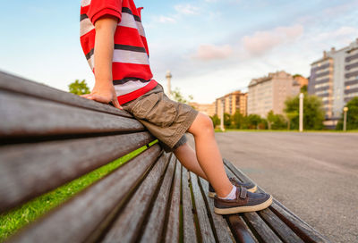 Low section of boy sitting on bench at park