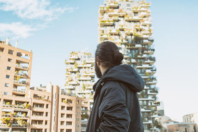 Rear view of man standing against buildings in city