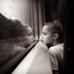 Thoughtful girl looking through window while traveling in train