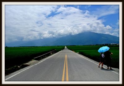 Road passing through landscape against cloudy sky