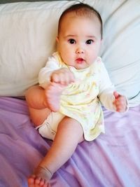 Portrait of cute baby girl lying on bed