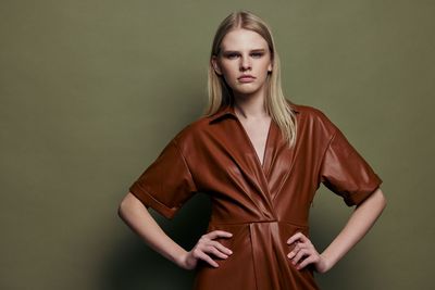 Portrait of young woman standing against wall