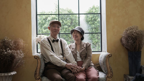 Portrait of friends smiling while sitting on sofa