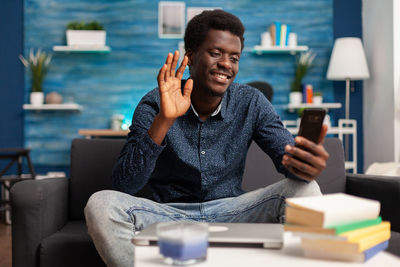 Young man using mobile phone while sitting on table