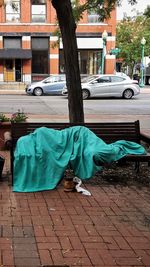 Man relaxing on sidewalk by street in city