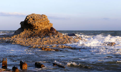 Rock formation in sea against sky