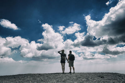 Rear view of couple photographing against sky