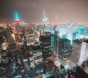 Illuminated modern buildings in city against sky at night