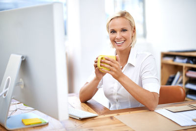 Smiling businesswoman having coffee during break at office